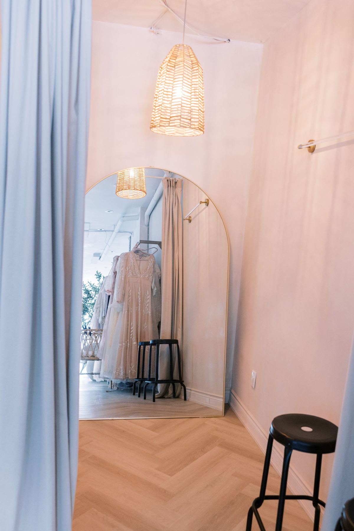 The private change room with an arched gold floor mirror and rattan pendant light